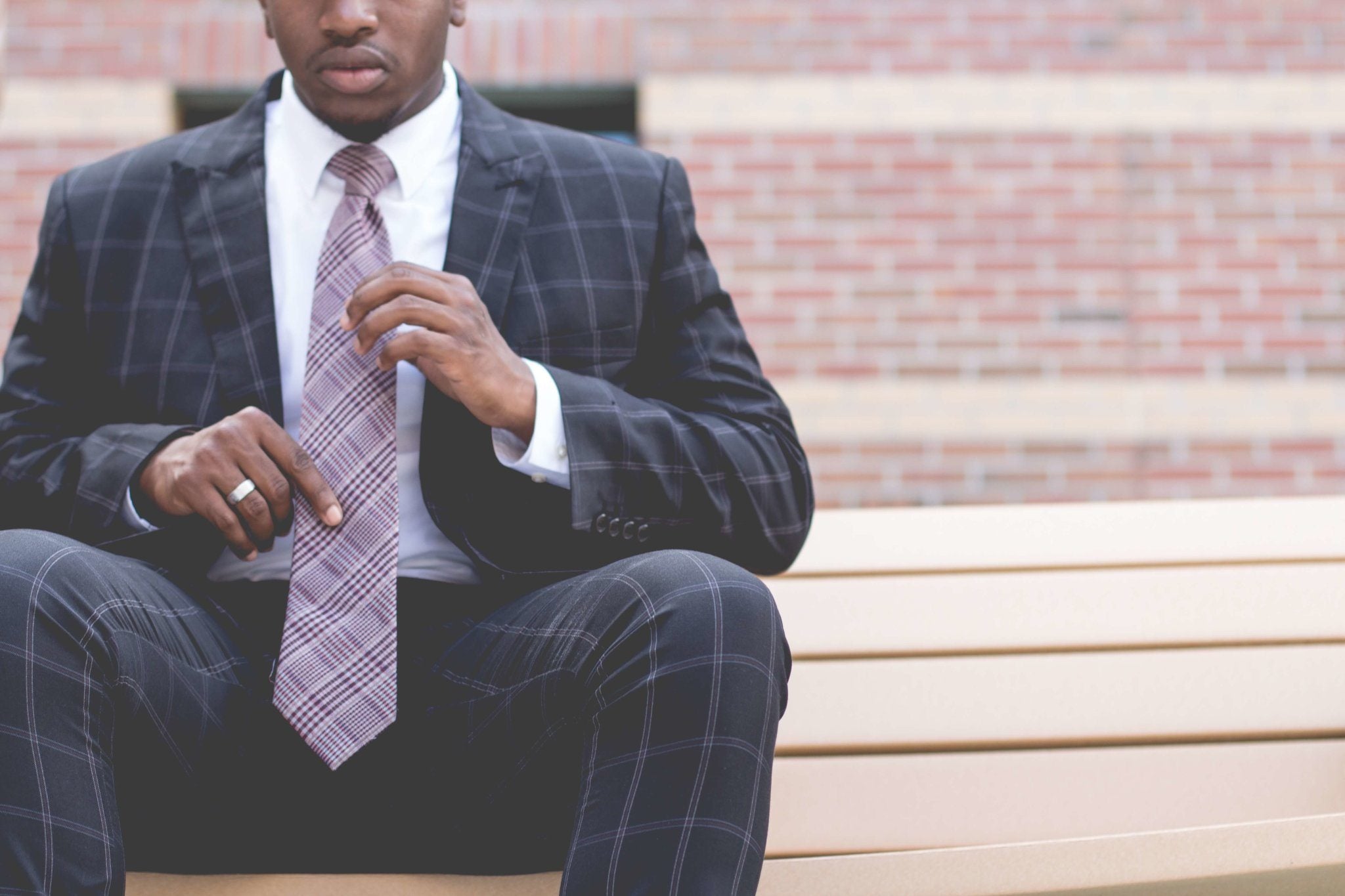Man in custom suit sitting on bench.